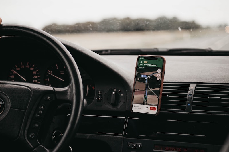 A view of the steering wheel, with a phone showing directions on a phone mount